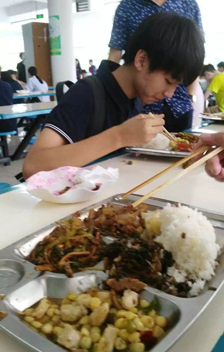 背着书包穿着校服在食堂吃饭,在教室与同学一起写作业,与普通学生无异