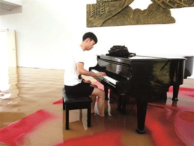 男生洪水中淡定弹钢琴 被赞现实版“海上钢琴师”