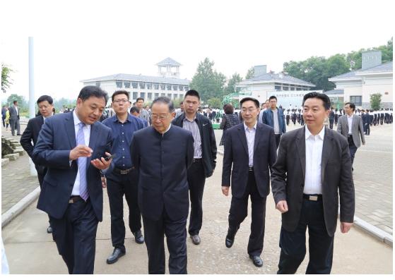 第十届全国政协副主席、中国国土经济学会理事长张怀西（中）听取信阳航空服务学校校长、学会航空经济发展委员会会长刘品生（左一）介绍校企合作模式创新发展情况