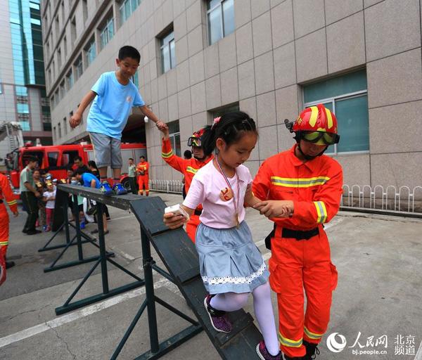 在消防员的保护下，小朋友体验过独木桥。