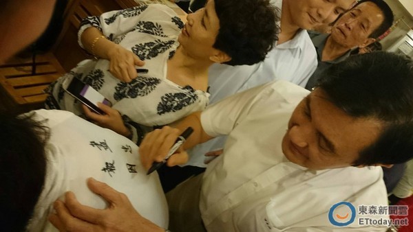 马英九在民众背后提笔写下“尽忠报国”