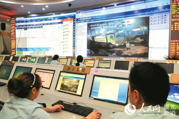 城管执法人员通过大屏幕监控渣土车。（肖敏 摄）