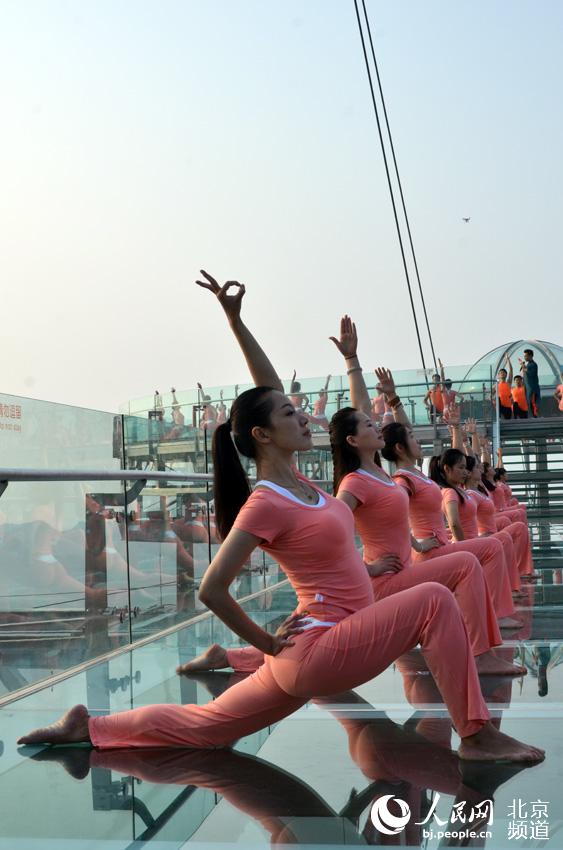伴着清晨的旭日，瑜珈爱好者在玻璃观景台上练起了瑜珈。人民网尹星云 摄