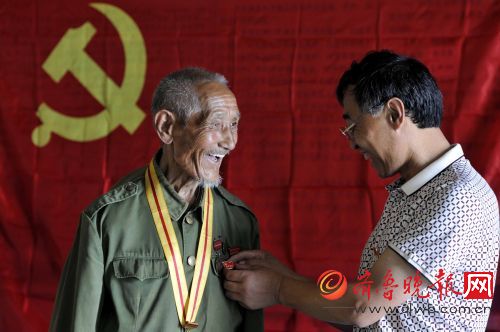 6月27日,临沂市郯城县马头镇东胜街党支部书记杨永刚为抗战老兵兰兆法(左)佩戴党章