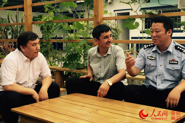 黄文祝（右一）和阿卜拉江·艾麦尔（左一）在警务站葡萄架下开心交谈。   胡仁巴  摄