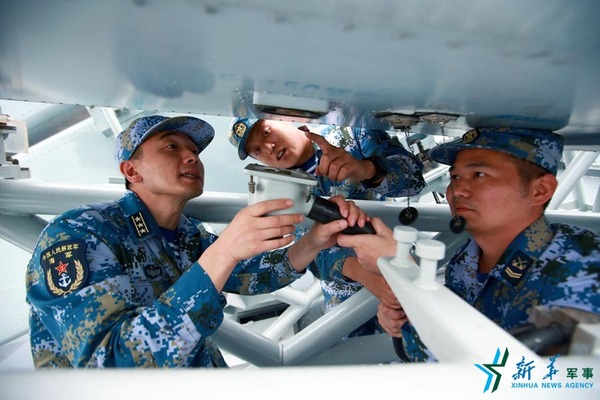 范文武（左一）在宿州舰与专业骨干研究装备性能。（2016年7月1日 ）新华社记者查春明摄