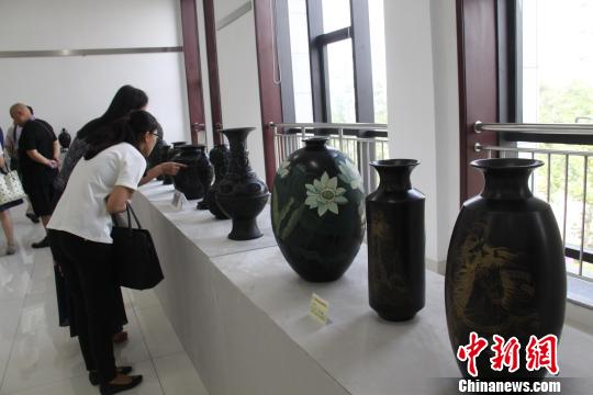 图为参赛作品陈列厅内，观众在仔细观察黑陶制品。　曾洁　摄