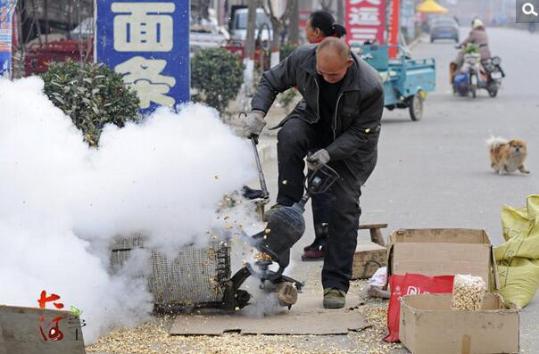 一位师傅在乡村集市上崩爆米花.