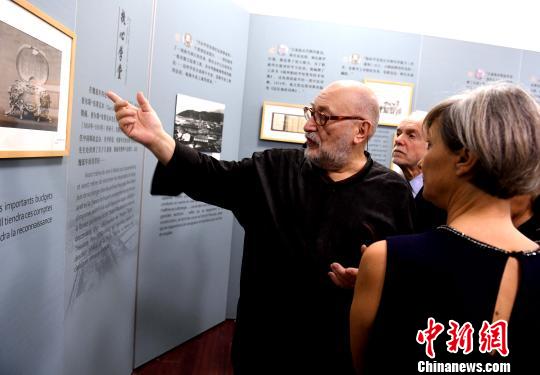 展厅内,法国友人魏延年(图中)仔细为观展的法国嘉宾介绍展览图片背后的故事。 记者刘可耕 摄