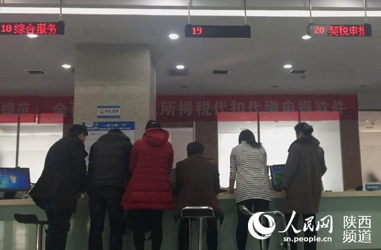 办事群众围在19号窗口前，18号和20号窗口均暂停服务。