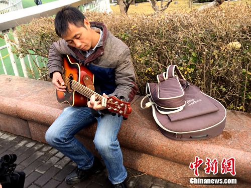 图为樊富贵在北京街头弹吉他，感谢出手相助的好心人。吕春荣 摄