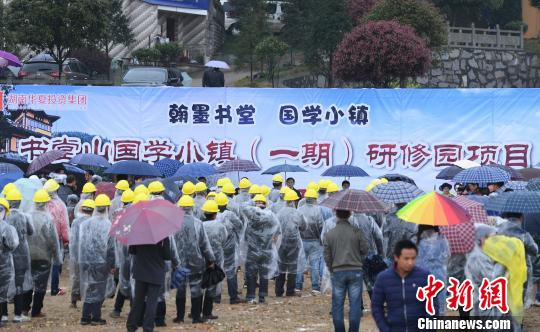 众人雨中参加国学小镇的开建仪式。　杨华峰　摄