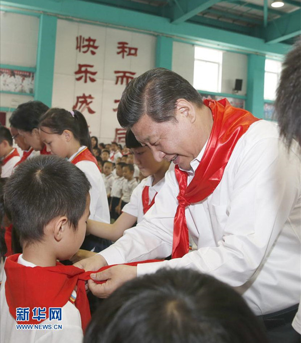 2014年5月30日，在北京市海淀区民族小学的少先队入队仪式上，习近平为新少先队员系上红领巾。新华社记者鞠鹏摄