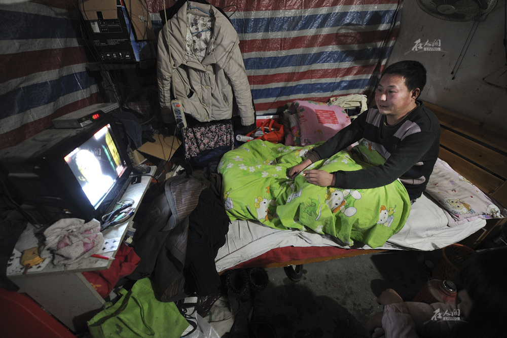 图为2012年1月9日,商城二楼被分割的房子里,一个打工者在看电视,这间