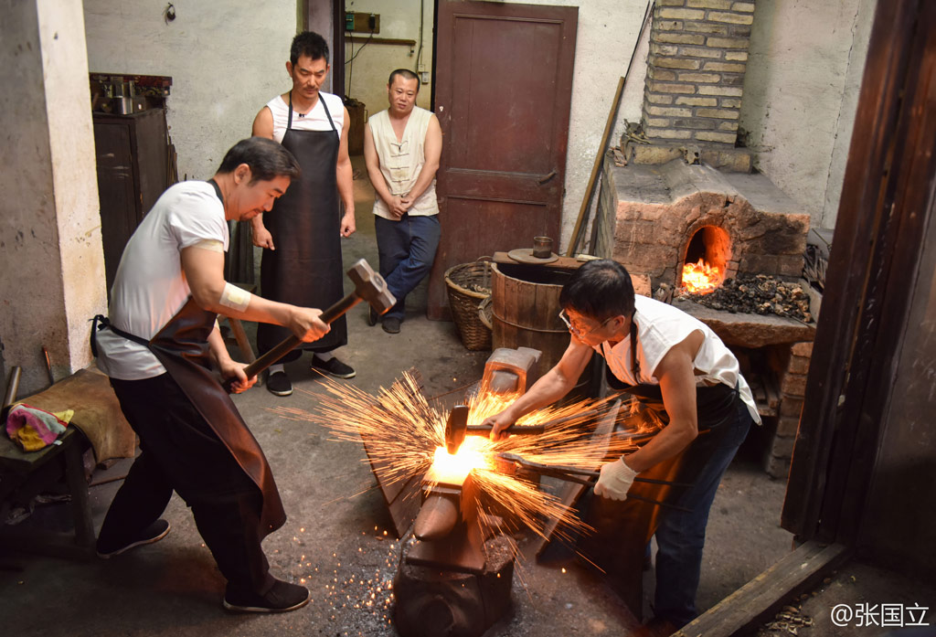 在节目中张国立用力打铁,火花四溅.(资料图)张国立听老师指导.