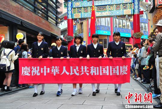 图为当地侨校学生手持庆祝国庆横幅参加游行 王健 摄