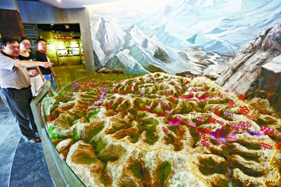人们在宝兴县红军翻越夹金山纪念馆观看翻越雪山路线沙盘.