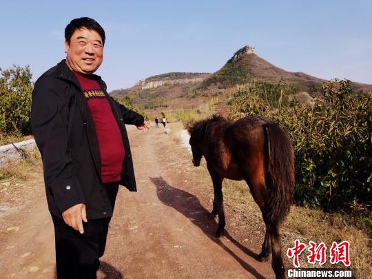 立志于乡村旅游创业的山东沂源农民王永宝,指着一匹小马说,远处的双